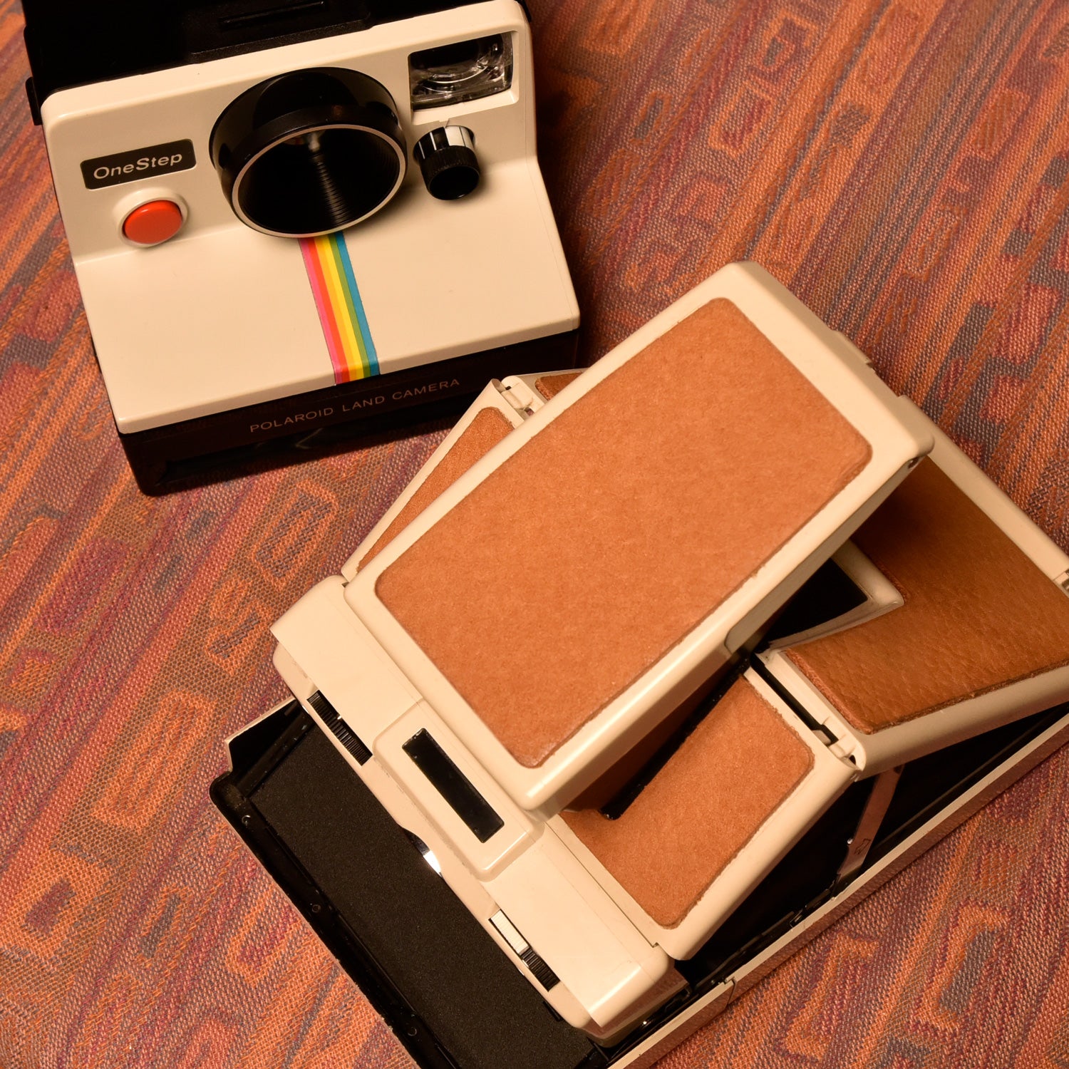 sx70 folding and rainbox box cameras sitting on southwest pattern